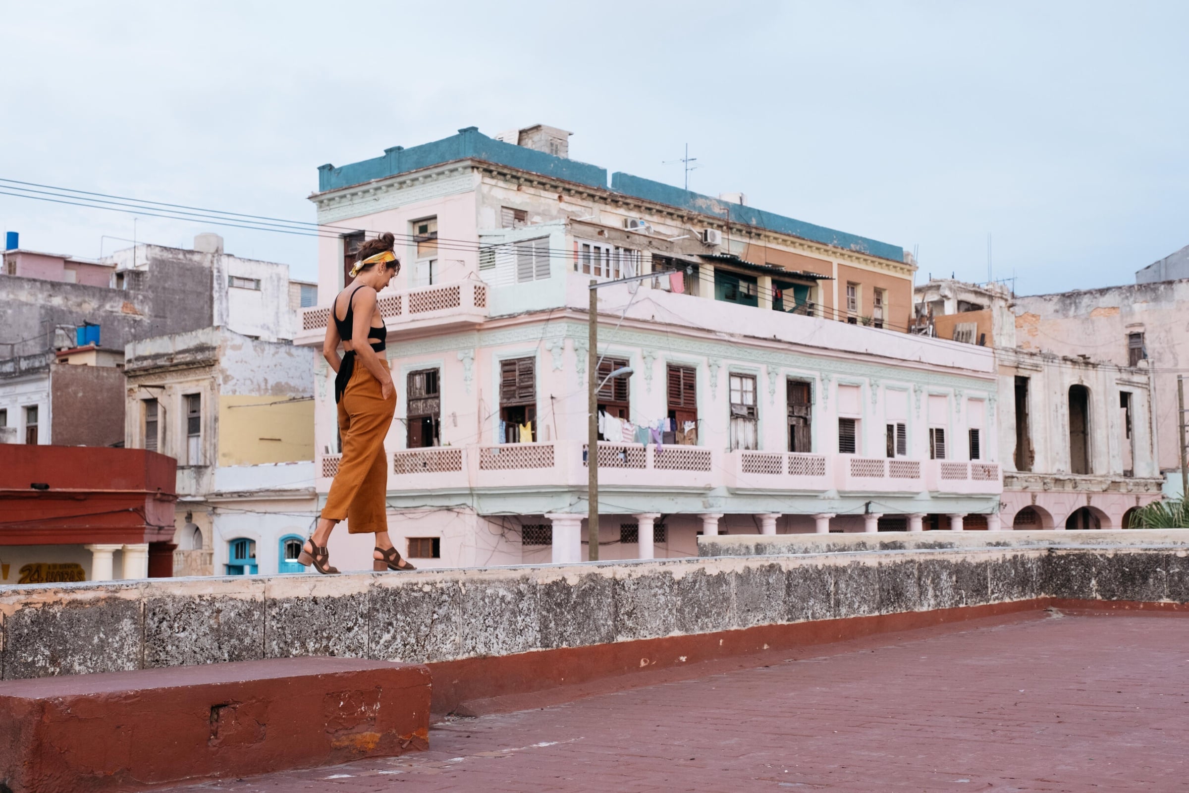 Pepper walks a Havana rooftop ledge in a rust-orange jumpsuit